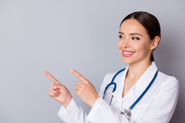 Closeup photo of cheerful family doc professional direct fingers look side empty space remind patients vaccination time wear medical uniform lab coat stethoscope isolated grey background