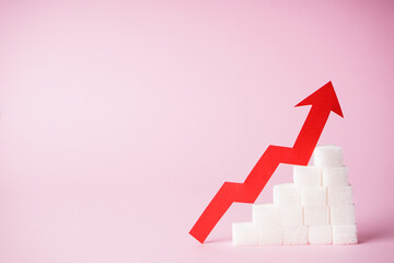 Increase in blood sugar levels, the graph of growth of the sugar cubes and arrow on top on a pink background with space for text. Diabetes concept.