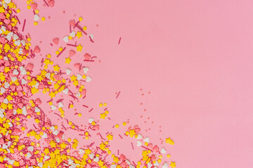 sprinkle topping in the form of stars and hearts on a gently pink background
