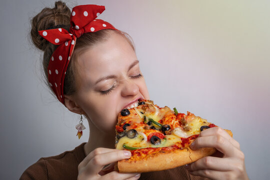 Young Caucasian woman girl biting devouring a big pizza slice. Hunger concept