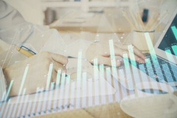 Multi exposure of stock market graph with man working on laptop on background. Concept of financial analysis.