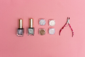 on a pink background there are nail polish and boxes with sparkles and scissors.
