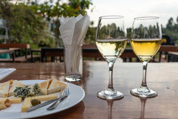 Two glasses of white wine with cheese platter in a terrace with vineyards view. Two grape varieties: Chardonnay and Sauvignon blanc. Red Mountain area, Inle lake, Myanmar, Burma, south east Asia