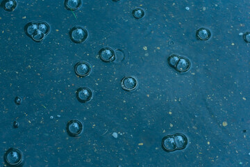 blue background puddle of rain / raindrops, circles on a puddle, bubbles in the water, the weather is autumn