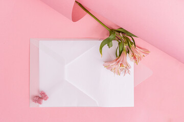 transparent white envelope on a light pink background with a flower
