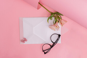 transparent white envelope with black glasses on a pink background with a flower
