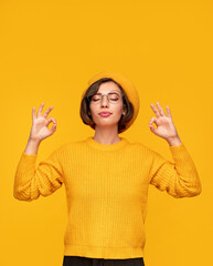 Happy young relaxed woman with eyes closed meditating in studio