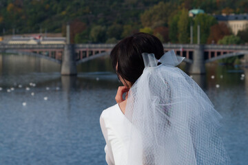 The bride admires Prague from Charles Bridge. Girl in a wedding dress with a veil.