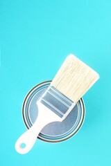 Paint brush with natural bristles for paint and metal can on blue background. House renovation. Hobby.