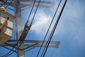 Electricity authority clean the ceramic insulator on the electric pole by high pressure washers.