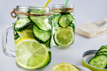 Cold drink, two retro glass jars of lemonade with cucumber and lemon against white background,...