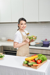 Portrait of a young and cheerful woman eating healthy salad on the kitchen at home