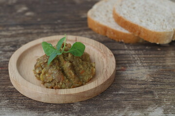 Vegan mushroom pate. Paste from Mushrooms and carrot and onionon wooden plate and two pieces of bred on wooden table.