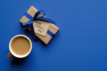 Vintage gift box with Happy Father's Day inscription and cup of coffee on blue background. Flat...