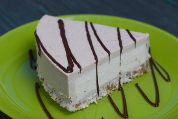 Cheesecake on a plate. Garnished with Chocolate. On brushed pine boards painted black and green.