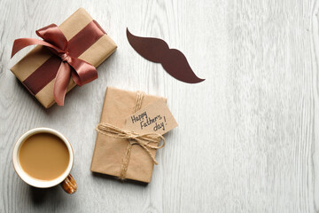 Happy Fathers Day concept. Gift box with label Happy Father's Day, mustache, cup of coffee on wooden table top view.