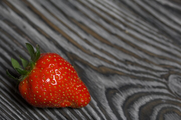 Red strawberry with green ponytails. On brushed pine boards painted in black and white.