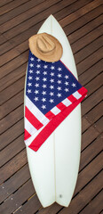 USA flag on a white surfboard, American stars & stripes & a straw cowboy hat. This is known as the Red, white, and blue. Surfing is a lifestyle. Patriot.