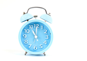 Alarm clock of blue pastel color with five minutes to twelve o'clock ,isolated on white background