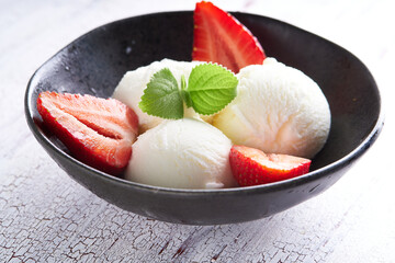 Vanilla ice cream with strawberries and almonds served in a plate