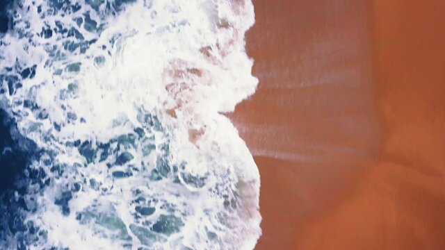 Flying over a sandy beach. Waves break on a sandy beach on the Atlantic coast, aerial View. Nazare, Portugal.