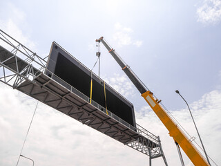 Construction site crane is lifting a led signboard for advertisement