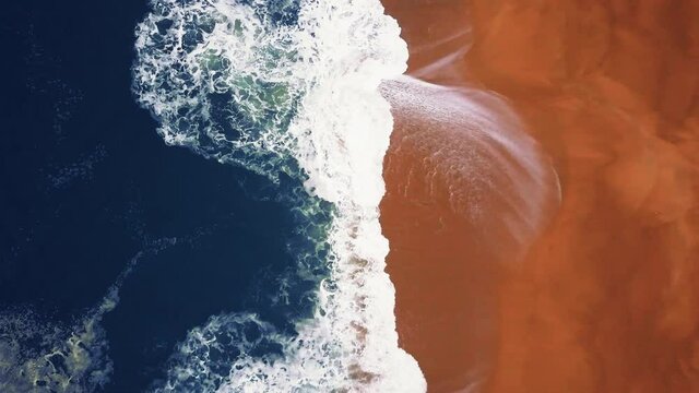 Flying over a sandy beach. Waves break on a sandy beach on the Atlantic coast, aerial View. Nazare, Portugal.