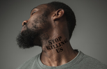 Close up black man tired of racial discrimination has tattooed slogan stop killing us on his neck....
