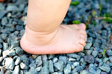 砂利の上に裸足で立つ赤ちゃんの足