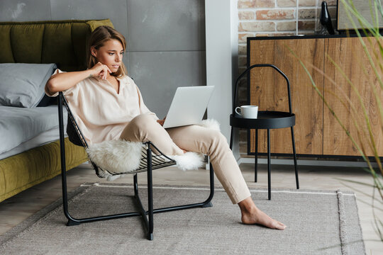 Image of nice woman working with laptop while sitting on armchair