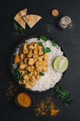 Indian Butter chicken curry with basmati rice in bowl on black background. Indian food concept. Flat lay, copy space
