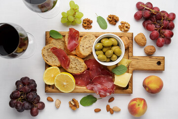 Wine snacks on a cutting board. Fresh bread, cold bresaol meat, lemon and parmesan cheese. Party appetiser