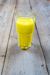 Golden milk in a glass cup on a wooden background