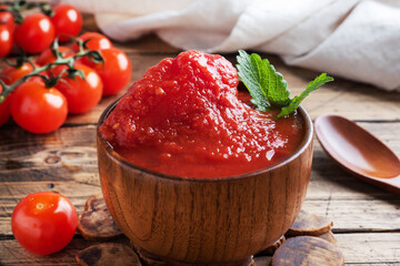 Tomatoes in their own juice or Tomato paste in a wooden bowl and fresh tomatoes on a rustic wooden table.