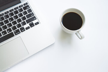White office desk table with laptop computer, cup of black hot coffee 