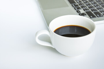 White office desk table with laptop computer, cup of black hot coffee 