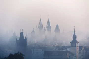 Rolgordijnen View of the centre of Prague and Charles bridge in the fog in the early morning with towers and silhouettes. Prague, Czech Republic © Denis Poltoradnev