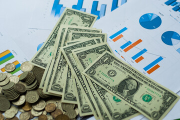 A lot of different banknotes of us dollars and Euro coins on the background of a sheet with financial charts. Natural photo.