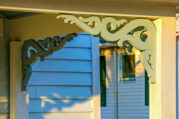 Close-up of the carved scrollwork on a pair of decorative porch brackets on an old wooden house.
