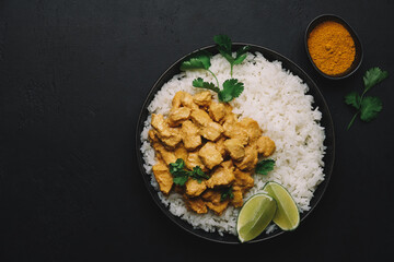 Indian Butter chicken curry with basmati rice in bowl on black background. Indian food concept. Flat lay, copy space