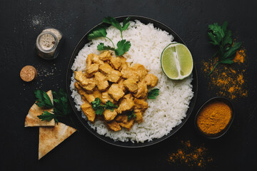 Indian Butter chicken curry with basmati rice in bowl on black background. Indian food concept. Flat lay, copy space