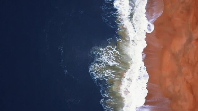Flying over a sandy beach. Waves break on a sandy beach on the Atlantic coast, aerial View. Nazare, Portugal.