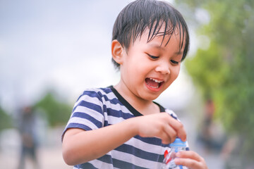 little boy smiling and opening bottle of water 