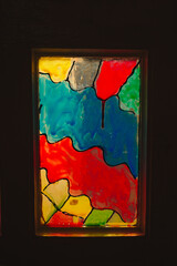 Square, multi-colored, old, hand made stained glass window. A small window with a stained glass window.