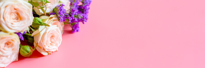 a bouquet of cream roses and bright purple flowers in full bloom on a pink background with space for text. greeting card. banner