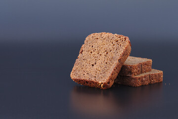 Freshly baked homemade bread on a black background. Slices of brown bread.