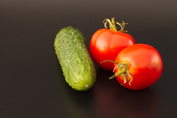 Fresh tomatoes and cucumbers on a black background