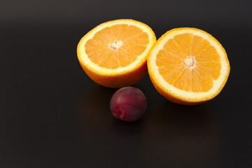 Orange and plum on a black background. Close-up. Healthy eating concept.