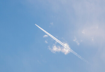airliner with contrails on a blue sky with clouds
