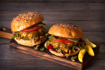 Beef burger in classic american style with hot grilled patty, melted cheese on top, tomato, onion, sauce and chips